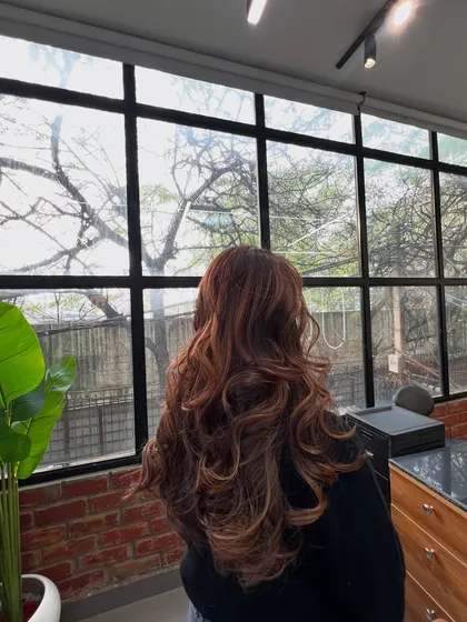 A beautiful example of a warm, reddish-brown balayage, styled with soft curls to show off the dimension.