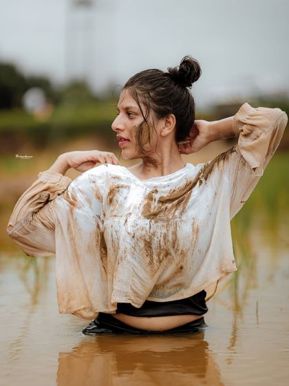 A candid moment from the mud shoot, capturing the model as she adjusts her hair. These in-between moments often add a layer of authenticity to a conceptual series.