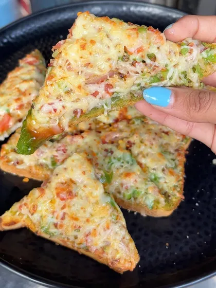 A hand holding a piece of my Open Cheese Chilli Toast, showing the generous topping of cheese and vegetables.