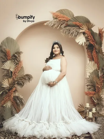 A stunning solo portrait of the mom-to-be in the same setup. She looks like a true queen, cradling her bump with a gentle smile.