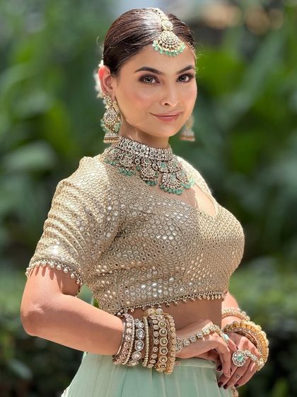 A close-up of a bride in a mint green lehenga. The makeup is fresh and dewy, with a focus on glowing skin.