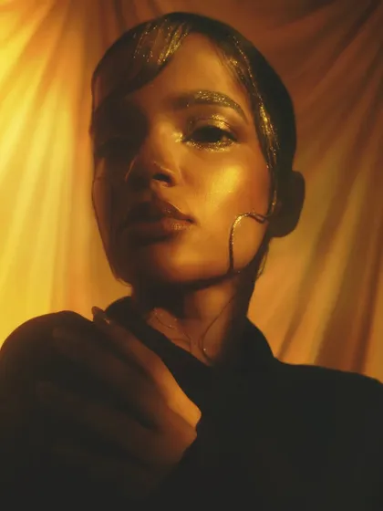 A moody, artistic shot that plays with shadow and light, with the gold makeup providing a stunning focal point.