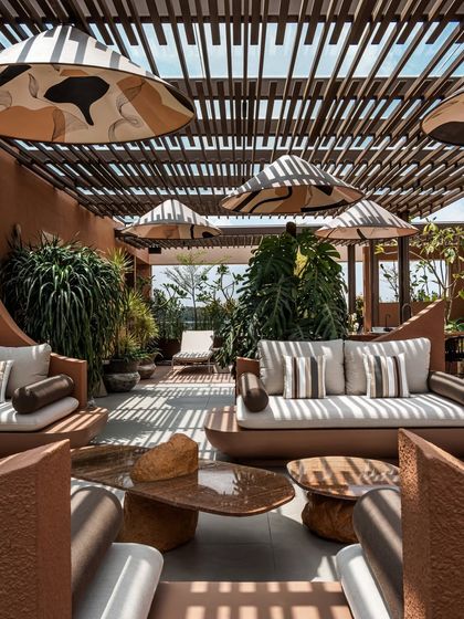 The play of light and shadow is a key design element. Here, the pergola casts graphic lines across the custom furniture and flooring, creating a dynamic visual effect that changes throughout the day.