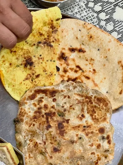 A delicious North Indian thali with a variety of breads like stuffed kulcha, missi roti, and naan.