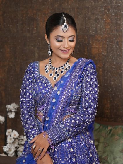 A soft, smiling portrait of the client in her blue sangeet outfit. The makeup focuses on a glowing base and beautifully defined eyes, making her look and feel radiant.