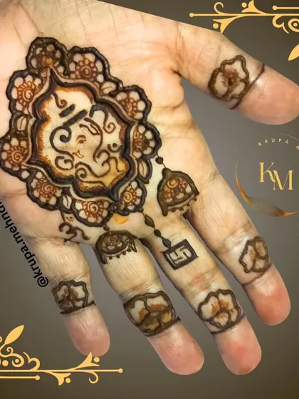 A minimalist Ganpati design with hanging jhumkas. This is a chic and modern way to wear your faith on your hands during festivals.