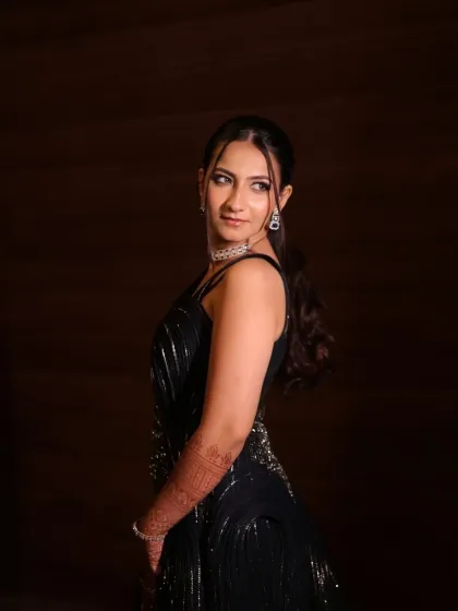 A chic side profile showing off the sleek ponytail and the structure of her glamorous gown. The makeup is flawless from every angle.