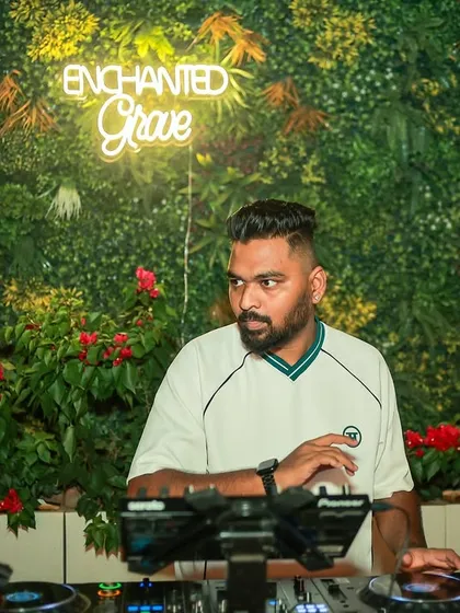 DJing in front of a lush green wall. I can set the mood in any environment, from industrial clubs to vibrant, decorated spaces.