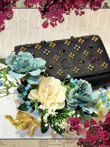 A close-up of the black studded handbag, framed by a floral border. This image highlights the beautiful texture of the bag and the delicate floral arrangement.