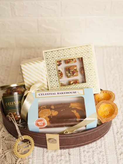Our 'Royal Basket' for Diwali is a luxe hamper featuring a marble tea cake, a box of handmade mithai, a jar of granola, and festive diyas, all arranged in a regal leather-finish basket.