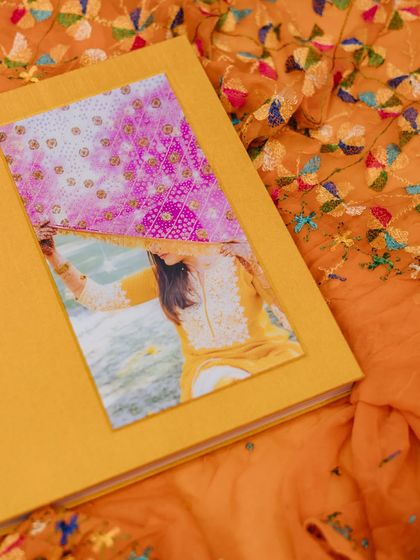 A close-up of a custom-made luxury wedding album, showcasing its yellow fabric cover and an inset photo.
