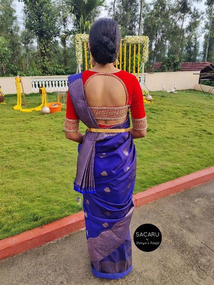 The back view of Thanni's ensemble, showing the elegant round cutout on her red velvet blouse, finished with detailed embroidery.