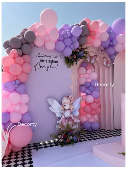 A beautiful fairy-themed backdrop with pink, purple, and grey balloons, perfect for "fluttering into 4."