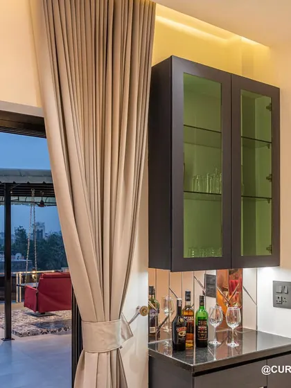 This lounge includes a compact and stylish bar corner. The glass-front cabinet is perfect for storing glassware, and its location provides easy access to the outdoor terrace.