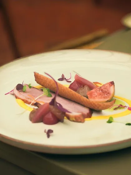 A delicate appetizer of cured duck breast with fresh figs and pickled pearl onions, served at a modern European breakfast event.