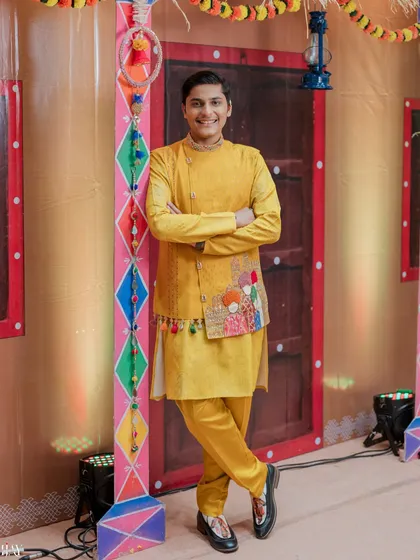The groom looking sharp and confident in his yellow jacket and kurta for the Haldi ceremony.
