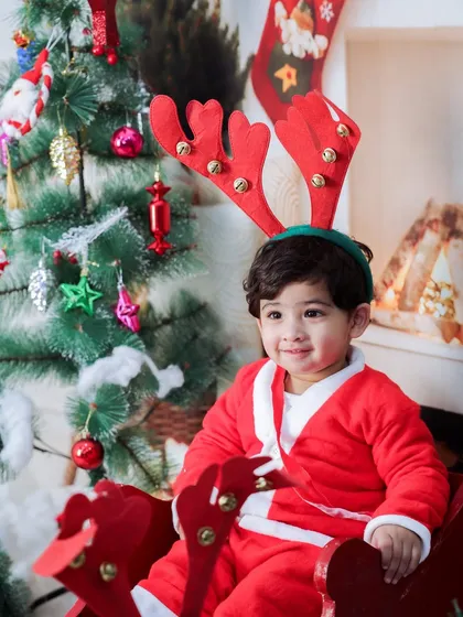 This little one is all smiles, dressed as Santa and wearing reindeer antlers. A joyful and fun-filled Christmas portrait.