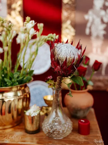 A unique floral detail featuring a striking protea flower in a glass vase, set against a backdrop of brass and terracotta. This shows our love for mixing traditional and exotic floral elements.