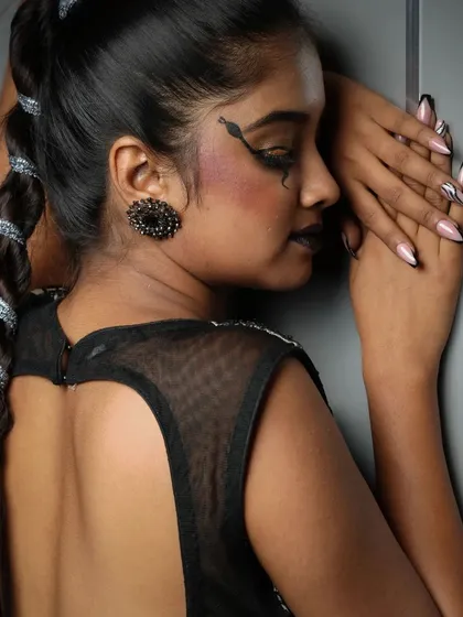 This side profile highlights the creative details, including a snake eyeliner design and a beautifully crafted braid, demonstrating a complete conceptual look.