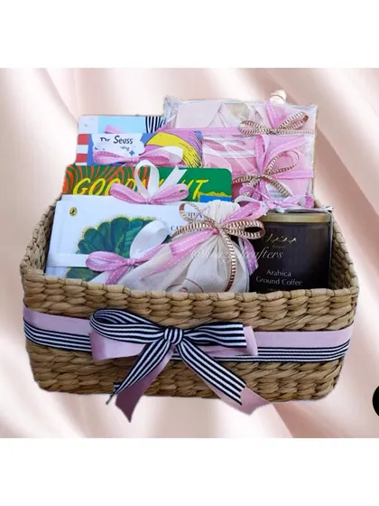 A luxury hamper for the mom-to-be, presented in a beautiful woven basket. It's filled with books, coffee, and other pampering items.