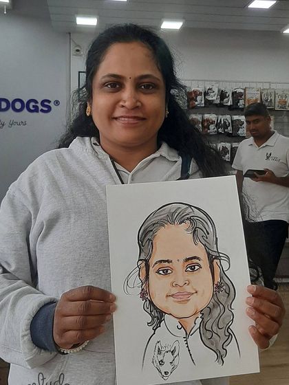 A proud pet owner holding her caricature, which includes a small portrait of her own furry friend.