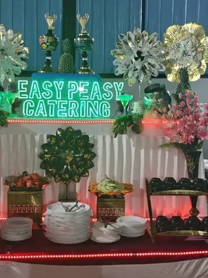 An elaborate dessert and fruit station for a festive gathering. Our illuminated "Easy Peasy Catering" sign adds a modern touch to the colorful and decorative setup.