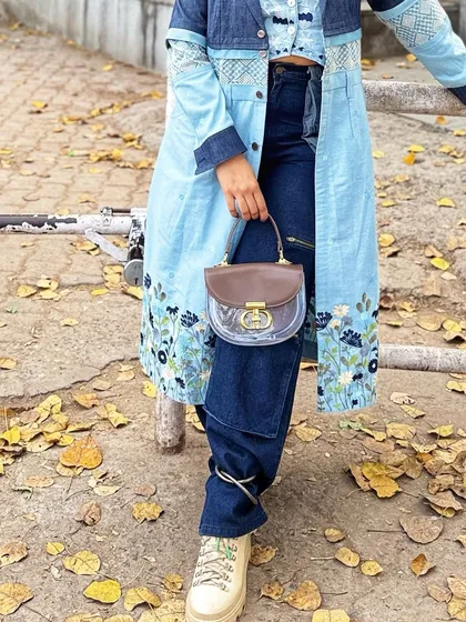 A detailed shot focusing on the lower half of the outfit, where the unique design of the purse is clearly visible against the dark denim.
