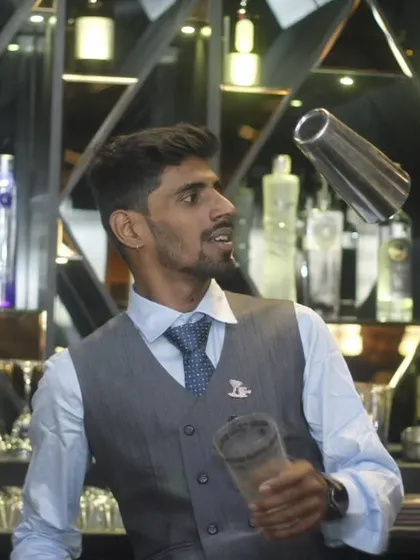 A flair bartender in his element, effortlessly tossing a shaker. This is the kind of entertainment and skill that elevates a standard bar service into a memorable performance.