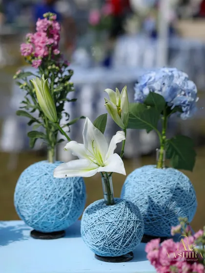 A trio of the charming handwoven thread vases, holding white lilies, pink snapdragons, and blue hydrangeas.