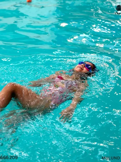 Little fish, big dreams. A young swimmer gracefully floats on her back during a race, showcasing her skills.