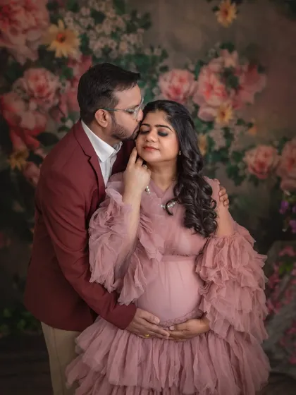 A tender moment between partners. His gentle kiss and her serene expression make this a heartwarming and romantic maternity portrait.