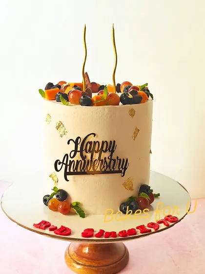 For special milestones, I create elegant cakes like this tall anniversary cake. It features a smooth buttercream finish, delicate gold leaf accents, and a generous topping of fresh, seasonal fruits, all completely eggless.