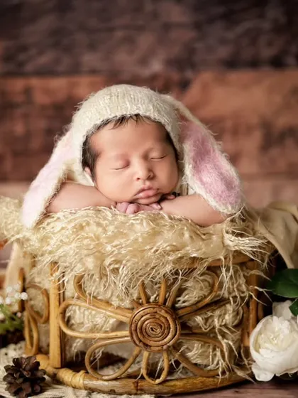 A sweet newborn in a bunny hat, resting in a rustic basket. We combine natural textures with soft fabrics to create warm and cozy newborn portraits.