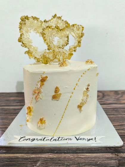 Bling for an engagement. I crafted these delicate, interlocking hearts from isomalt crystals to create a stunning, modern topper for this elegant white and gold congratulations cake.