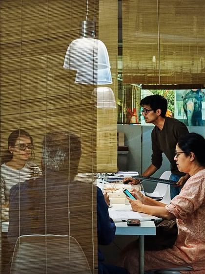 A meeting takes place in my Mumbai studio, viewed through layers of bamboo screens and reflections. The design creates a sense of privacy without complete separation, fostering a collaborative and open studio culture.
