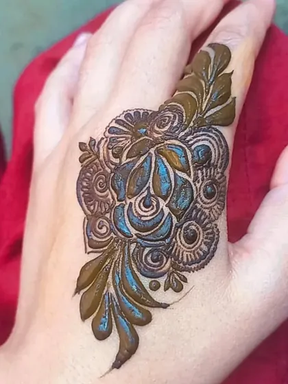 This is a single, bold rose design on the back of the hand. It's a statement piece, combining a central flower with leafy accents for a very artistic and modern henna look.