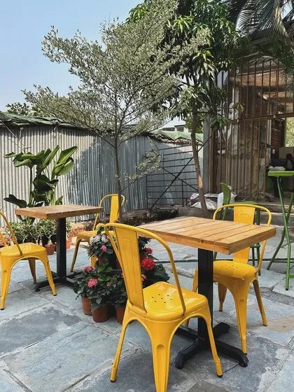 Our outdoor seating area is perfect for enjoying the pleasant weather. Surrounded by trees and potted plants, it's a great spot to work, chat, or simply enjoy a quiet moment.