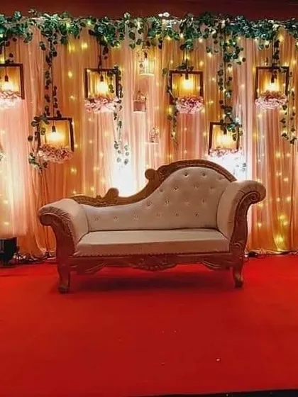 An elegant stage for a ring ceremony or reception. This design features a backdrop of soft drapes and fairy lights, with beautiful hanging lanterns and a classic chaise lounge, creating a warm and romantic ambiance perfect for photographs.
