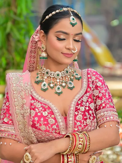 A vibrant look featuring a stunning Kundan and green bead jewellery set against a bright pink lehenga. This combination is perfect for a bride who loves bold colors.