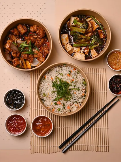 A complete meal for two, beautifully arranged. It includes two main courses, a bowl of fried rice, and a variety of our signature dipping sauces, all ready to be enjoyed.