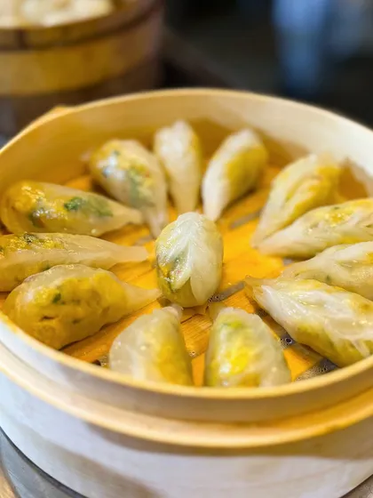A bamboo steamer filled with assorted dim sum. The different shapes and colours indicate a variety of fillings, promising a delightful tasting experience for guests.