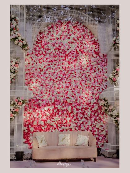 A beautiful photo booth setup with a wall completely covered in pink and white roses.