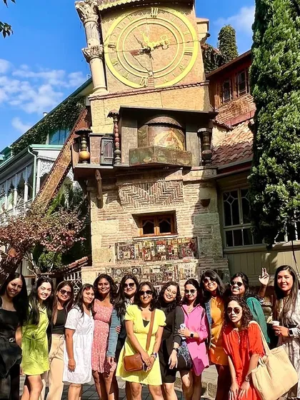 A girls' trip to Georgia is always special. Here's our group posing in front of the quirky leaning clock tower in Tbilisi, a perfect photo opportunity.
