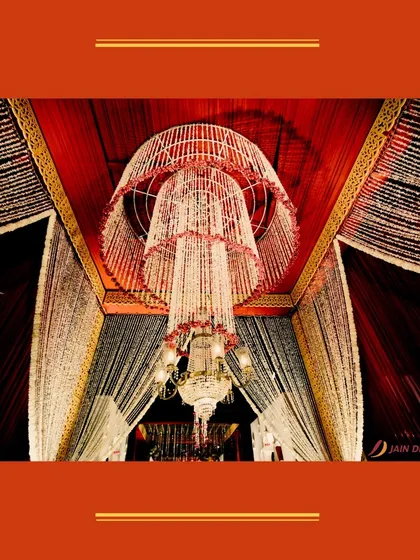 A grand floral chandelier made of white and pink tassels, hanging above a crystal chandelier. This layered design adds depth and opulence to the ceiling decor.