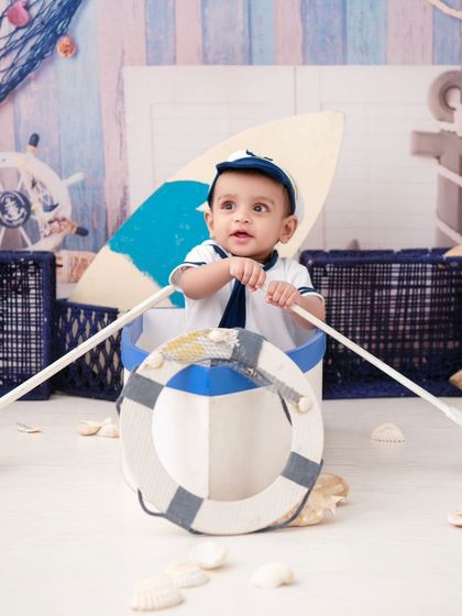 A little sailor on his boat. The nautical theme, with its ropes, shells, and soft blue tones, is perfect for a classic boy's photoshoot.