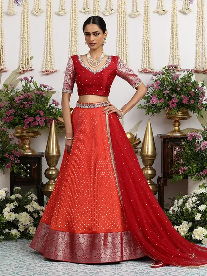 The side view shows how the red dupatta drapes beautifully, complementing the orange lehenga.