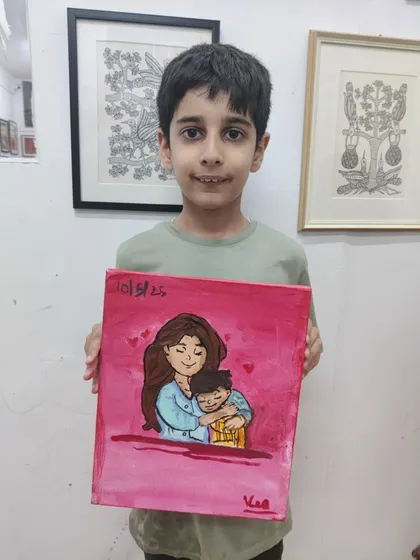 A young boy proudly displays the heartfelt painting he made for his mom. Our Mother's Day workshop is all about creating with love.