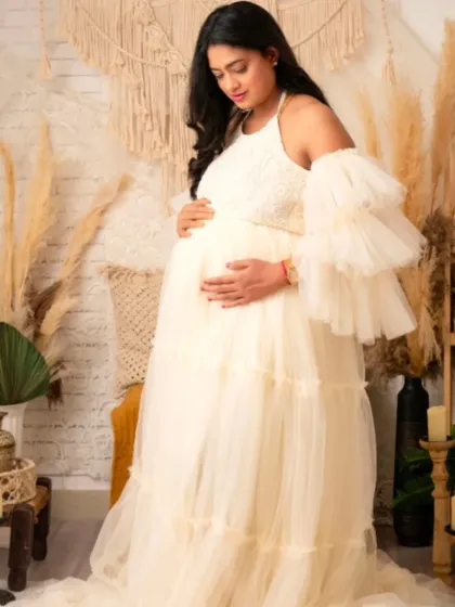 A serene portrait of a mom-to-be in our cream-colored ruffled gown, set in a bohemian-inspired studio.