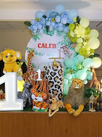 A cheerful jungle animal party setup for Caleb's first birthday. This stage decoration is filled with friendly plush and foil animals, a large light-up number one, and a custom backdrop.