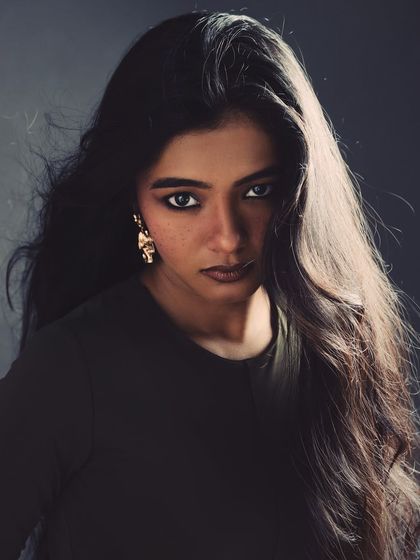 A powerful, direct-gaze portrait where the model's voluminous hair and intense eyes are the focus. The wind machine and simple lighting setup create a sense of drama and movement, resulting in a captivating and strong image.